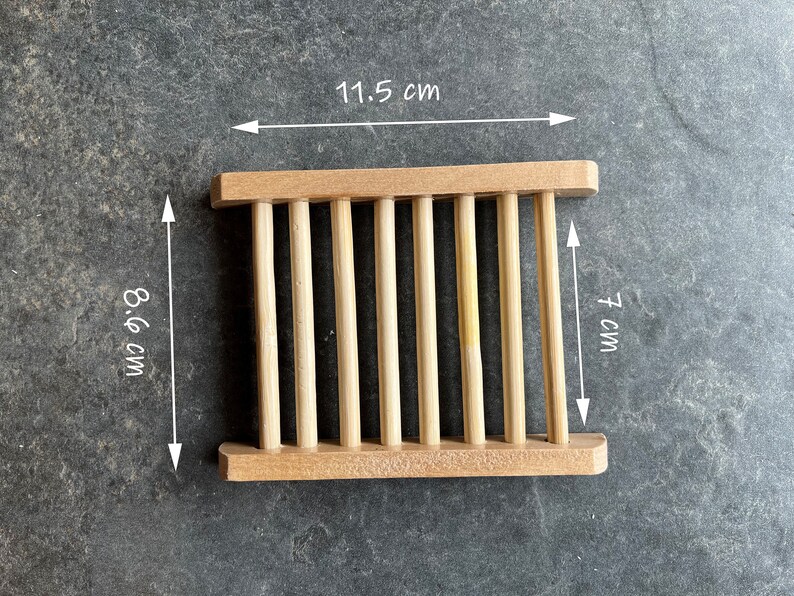 Op de afbeelding: Een houten zeepbakje met een lamellenontwerp. Het bakje is 11,5 cm breed, 8,6 cm lang en 7 cm hoog.