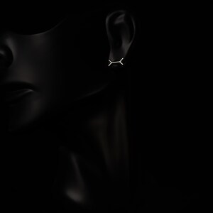 May include: A pair of minimalist silver earrings with a simple geometric design. The earrings are small and delicate, and they are perfect for everyday wear.
