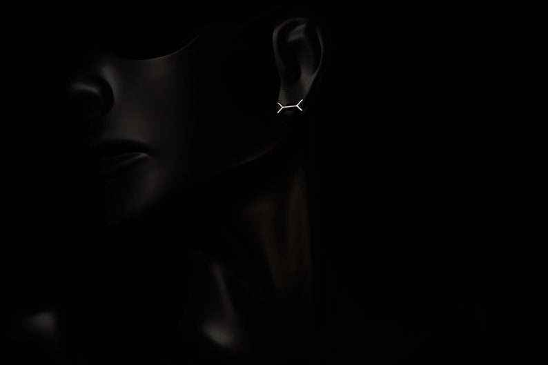 May include: A pair of minimalist silver earrings with a simple geometric design. The earrings are small and delicate, and they are perfect for everyday wear.