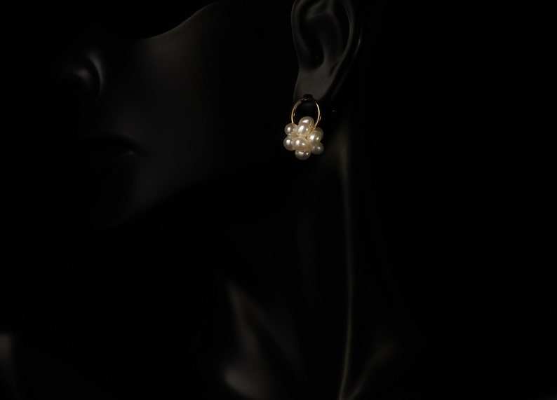 Peut inclure: Une paire de boucles d'oreilles cr&eacute;oles en or avec un groupe de perles blanches suspendues &agrave; chaque cr&eacute;ole.