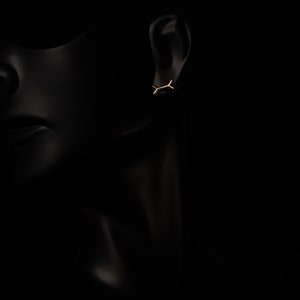 May include: A pair of gold earrings with a simple, minimalist design. The earrings are small and delicate, and they are perfect for everyday wear.