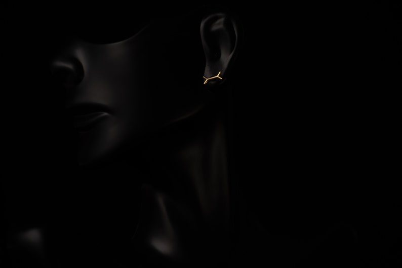 May include: A pair of gold earrings with a simple, minimalist design. The earrings are small and delicate, and they are perfect for everyday wear.