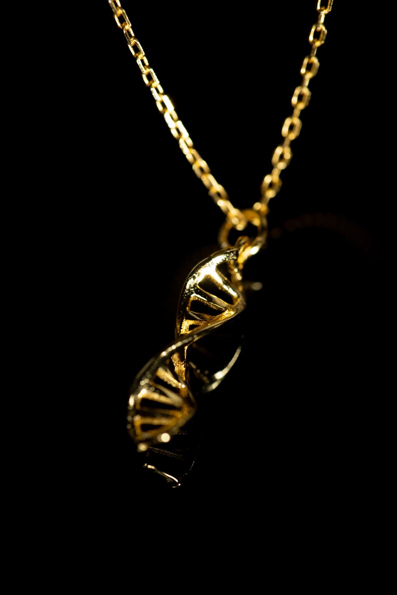 May include: A gold chain necklace with a pendant shaped like a DNA double helix.