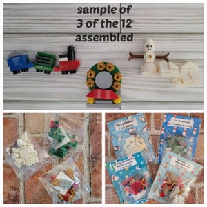 May include: Three assembled Lego Christmas ornaments: a train, a wreath, and a snowman. The ornaments are displayed on a wooden surface. The ornaments are packaged in small plastic bags with labels that say "Happy Holidays!" and "Let's build some BLOCK to BLOCK Holiday fun!"
