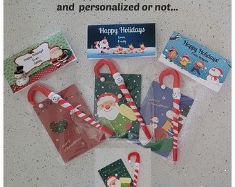 May include: Three Christmas card toppers with candy cane pens. The toppers feature Santa Claus, a snowman, and a group of children. The text on the cards reads "Happy Holidays" and "Merry Christmas".