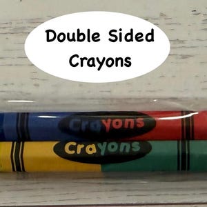 May include: Two double-sided crayons in a clear plastic package. One crayon is blue and red, the other is yellow and green. The word "Crayons" is printed on each crayon. The package has the text "Double Sided Crayons".