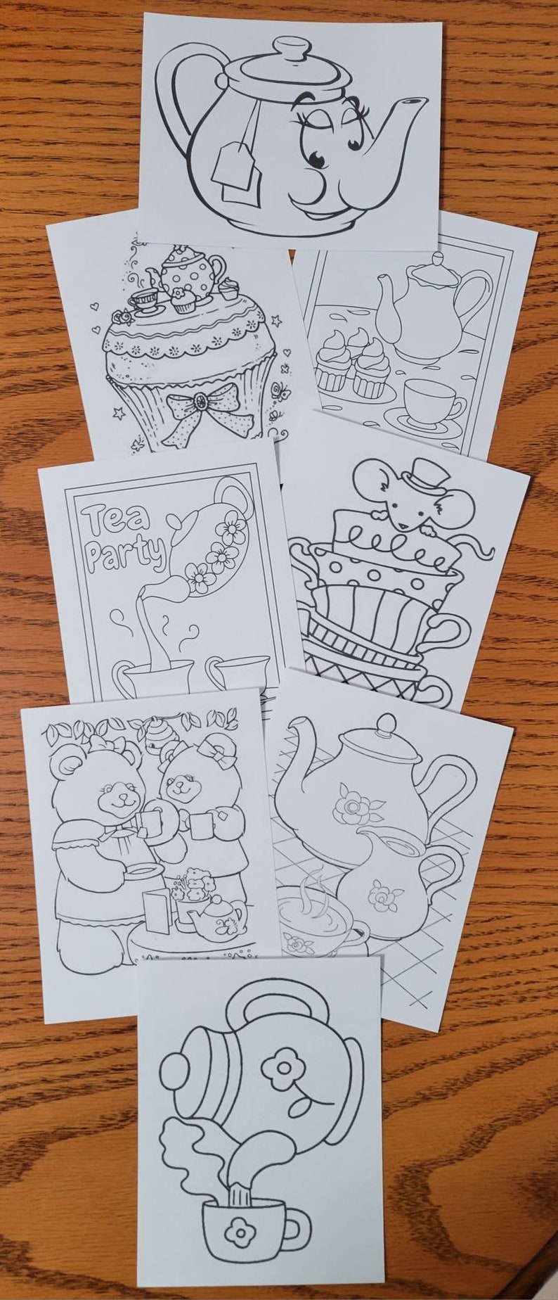 May include: A collection of black and white line art drawings featuring tea-themed illustrations. The drawings include teapots, teacups, cupcakes, and teddy bears, perfect for coloring or crafting projects.