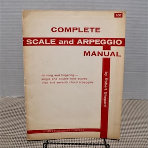 May include: A vintage music manual titled "COMPLETE SCALE and ARPEGGIO MANUAL" by Robert Shepard. The cover is off-white with red text and accents. The text includes "forming and fingering" and "SUMMY PUBLISHING COMPANY".