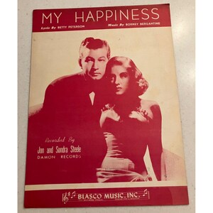May include: Vintage sheet music cover titled "MY HAPPINESS" with a red and white color scheme. The cover features a black and white image of a man and woman. The lyrics are by Betty Peterson, and the music is by Borney Bergantine. Recorded by Jon and Sondra Steele.