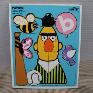 Può includere: Un puzzle vintage di Bert di Playskool con Bert di Sesame Street. Il puzzle ha 11 pezzi e include immagini di un'ape, una farfalla, una mazza da baseball, una palla da baseball, un uccello viola e un palloncino rosa con la lettera "b".