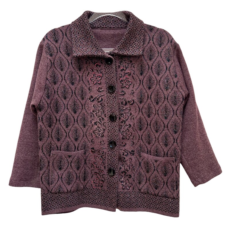 Puede incluir: Una chaqueta de punto de color morado con un dise&ntilde;o floral negro y rosa. La chaqueta tiene un cierre de botones y dos bolsillos.