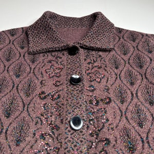 Puede incluir: Un c&aacute;rdigan marr&oacute;n con un dise&ntilde;o estampado en blanco y negro. El c&aacute;rdigan tiene cuello y botones. La tela tiene una textura brillante.