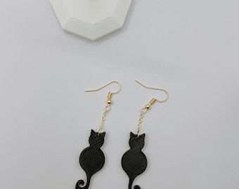 May include: A pair of black cat silhouette earrings with gold hooks and chains.