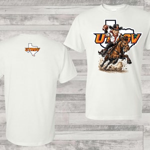 May include: White t-shirt featuring a cartoon cowboy riding a horse, with the text "UTRGV" in orange and blue. The back of the shirt displays the UTRGV logo in orange and white. The shirt is made of a soft, comfortable material.