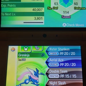 Peut inclure: Une capture d'écran d'un jeu Nintendo 3DS montrant un Pokémon Greninja de niveau 36. Le Pokémon est bleu et vert avec une écharpe rose. Les statistiques du Pokémon sont affichées sur l'écran du haut, y compris ses PV, son attaque, sa défense, son attaque spéciale, sa défense spéciale et sa vitesse. L'écran du bas montre les mouvements du Pokémon, qui comprennent Shuriken d'eau, Ace aérien, Double équipe et Éclair noir.