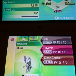 May include: A screenshot of a Nintendo 3DS game screen displaying a Meloetta Pokemon at level 15. The Pokemon is green and white with a pink flower on its head. The screen also shows the Pokemon's stats, including HP, attack, defence, special attack, special defence, and speed. The Pokemon's moves are listed below the stats, including Sing, Psychic, and Close Combat.
