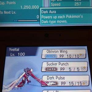 May include: A handheld gaming device screen displays a Pokémon battle interface. The screen shows the Pokémon Yveltal, a dark and flying type, with its stats and moves. The game interface includes the HP, Attack, Defense, Sp. Atk, Sp. Def, and Speed stats.