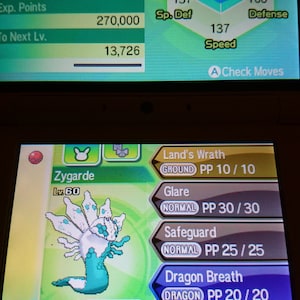 May include: A screenshot of a video game showing a Zygarde Pokemon with a level of 60. The Pokemon is green and white with a dragon-like appearance. The screen also shows the Pokemon's stats, moves, and abilities. The Pokemon's ability is Aura Break and it is holding a Life Orb.