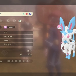 May include: A pink and blue Sylveon Pokemon character with large ears and a bow. The Pokemon is level 17 and is a Fairy type. The Pokemon's stats are listed, including its height of 5'7" and weight of 105.7 lbs.