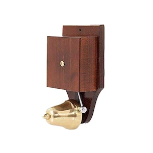 Op de afbeelding: Een deurbel in vintage-stijl met een donkerhouten montage en een gepolijste messing bel. De bel is met een metalen staaf en een kleine bal aan het hout bevestigd. Het hout heeft een vierkant blok en een decoratieve basis.
