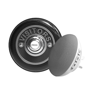 Könnte beinhalten: Eine schwarze und silberne Türklingel mit dem Wort "VISITORS" in weißen Buchstaben. Die Türklingel hat einen runden Knopf mit der Aufschrift "PRESS". Neben der Türklingel befindet sich ein kleiner, runder, grauer Lautsprecher.