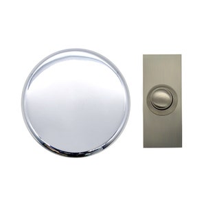 Puede incluir: Un botón de timbre redondo de plata con un botón redondo más pequeño de plata en el centro. El botón de timbre está montado en una placa rectangular de níquel cepillado.