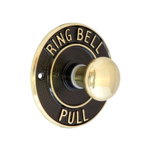 May include: A brass doorbell button with a black background. The button has the words "Ring Bell" and "Pull" inscribed on it.