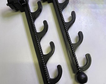 May include: Two black metal rod-style gun racks with five hooks each. The hooks are made of black plastic and have a rounded end. The rods are attached to a black plastic base with a threaded screw.