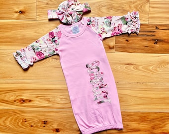 May include: Pink baby gown with floral print sleeves and the name "Scarlett" embroidered on the front.