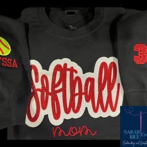 May include: Black sweatshirt with red and white embroidered softball design, the word "mom" and the number "30". One sleeve has a yellow softball and the name "Alyssa" embroidered on it.