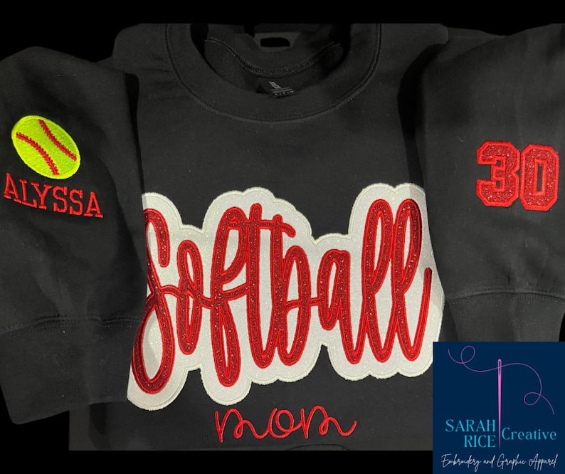 May include: Black sweatshirt with red and white embroidered softball design, the word "mom" and the number "30". One sleeve has a yellow softball and the name "Alyssa" embroidered on it.