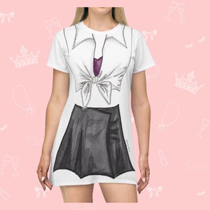 Peut inclure: Robe t-shirt blanche avec une jupe noire et un nœud papillon violet imprimé dessus. La robe a des manches courtes et un col rond.