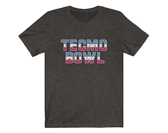 May include: A dark heather grey t-shirt with the words "Tecmo Bowl" printed in white letters with red and blue stars.