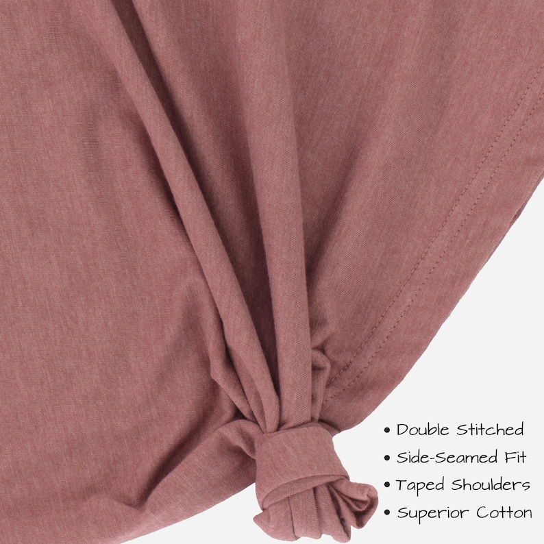 May include: Close-up of a mauve-colored t-shirt fabric with a knotted section. The fabric is described as double stitched, side-seamed fit, taped shoulders, and superior cotton.