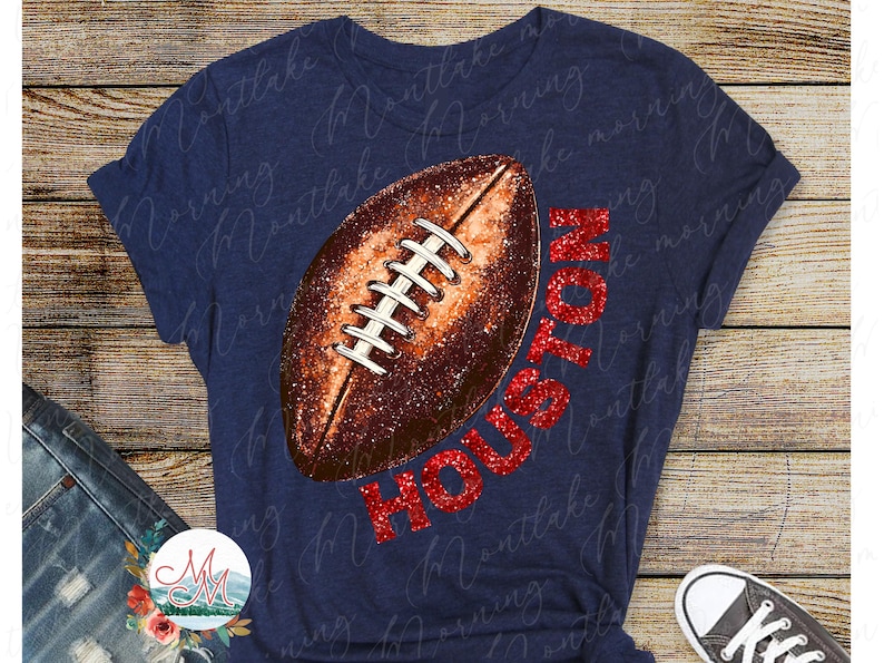 K&ouml;nnte beinhalten: Marineblaues T-Shirt mit einem Football-Design und dem Wort "HOUSTON" in rotem Glitzer. Der Football ist braun mit wei&szlig;en Schn&uuml;rsenkeln. Ein l&auml;ssiges T-Shirt f&uuml;r Sportfans.