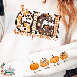 Può includere: Felpa bianca a maniche lunghe con la scritta "This Gigi loves her pumpkins" in un design a tema autunnale. La manica presenta illustrazioni di zucche con nomi. Un capo d'abbigliamento a tema autunnale.