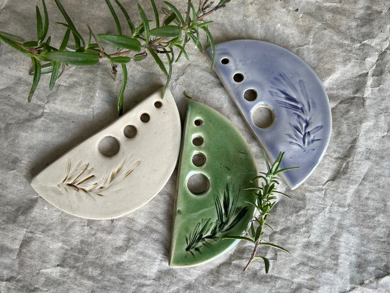Puede incluir: Tres piezas de vajilla de cer&aacute;mica en forma de semic&iacute;rculo con un dise&ntilde;o de hojas. Cada plato tiene cinco agujeros y est&aacute; esmaltado en un color diferente: blanco, verde y azul claro.