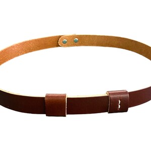 May include: A brown leather belt with a buckle and two adjustable straps. The belt is made of a soft, supple leather and has a classic design.
