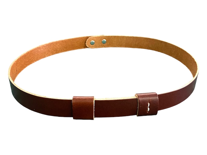 May include: A brown leather belt with a buckle and two adjustable straps. The belt is made of a soft, supple leather and has a classic design.