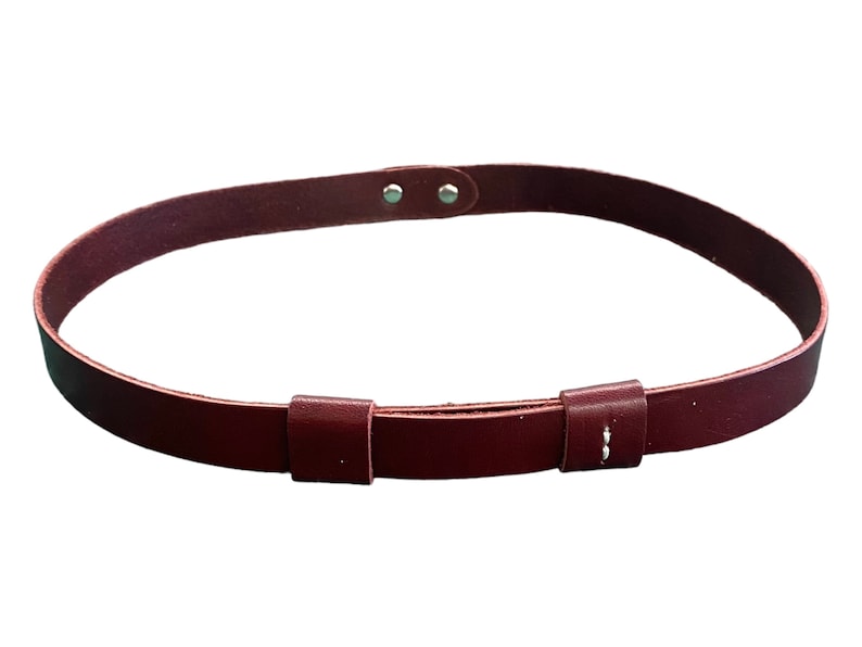 May include: A burgundy leather belt with two adjustable buckles. The belt is made of a soft, supple leather and has a simple, classic design.