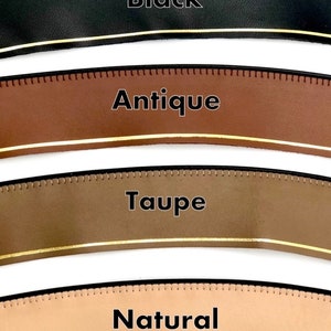 May include: Four leather straps in different colours: black, antique brown, taupe, and natural. Each strap has a gold line running along the edge.