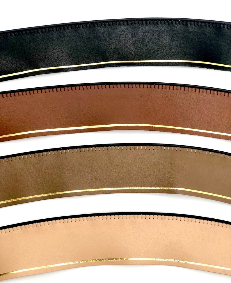 May include: Four leather straps with a gold trim and stitched edges. The straps are black, brown, olive green, and beige.