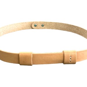 May include: A light brown leather belt with two adjustable straps and two metal rivets.
