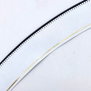 May include: White leather strap with a black stitched edge and a gold trim.
