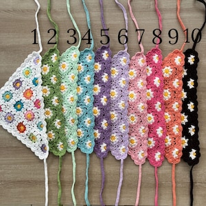 May include: Ten crocheted headbands with a daisy pattern in various colors, including green, light blue, purple, pink, and black. The headbands are numbered 1 through 10.