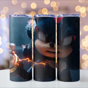 Puede incluir: Juego de tres vasos de acero inoxidable con la imagen de Shadow the Hedgehog. El dise&ntilde;o presenta al personaje en azul oscuro y negro con detalles en rojo y un efecto de rel&aacute;mpago. Los vasos tienen tapas transparentes.