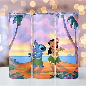 Puede incluir: Tres vasos de acero inoxidable con una escena de playa tropical con personajes de dibujos animados. El dise&ntilde;o incluye una criatura azul extraterrestre y una ni&ntilde;a con falda de hierba, sobre un fondo de puesta de sol con palmeras. Los vasos son cil&iacute;ndricos y tienen una tapa transparente.