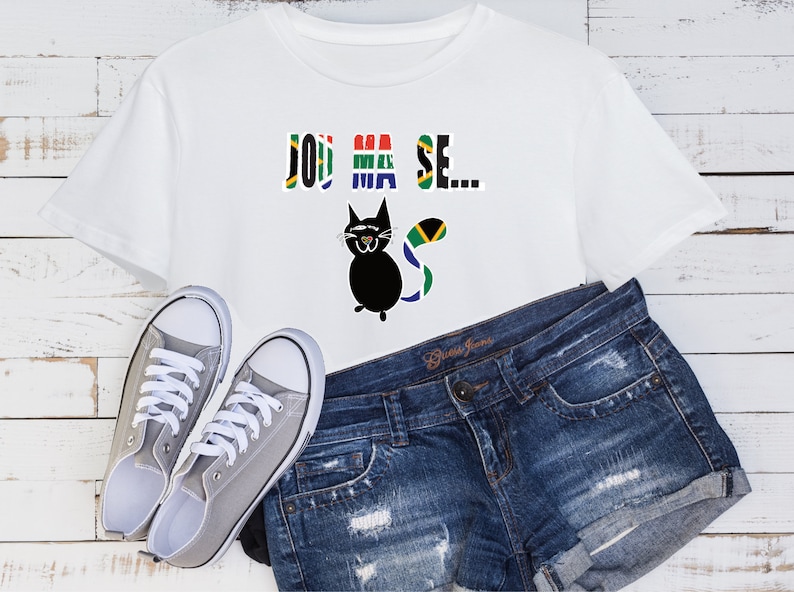 Pu&ograve; includere: Maglietta bianca con un gatto nero che indossa una coda di bandiera sudafricana e la scritta "Jou Ma Se..." stampata sul davanti. La maglietta &egrave; abbinata a pantaloncini di jeans blu e scarpe da ginnastica di tela grigie.