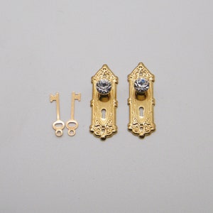 May include: Two gold-toned door knob plates with a crystal knob and keyhole. Two gold-toned keys are included.