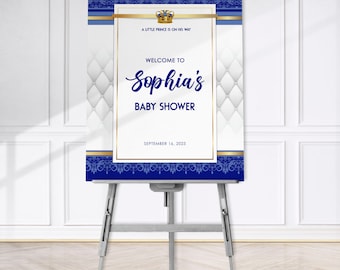 Puede incluir: Un cartel de bienvenida para una baby shower azul y dorado con fondo blanco y un patrón acolchado. El cartel dice "Un pequeño príncipe está en camino. Bienvenida a la baby shower de Sophia. 16 de septiembre de 2023."